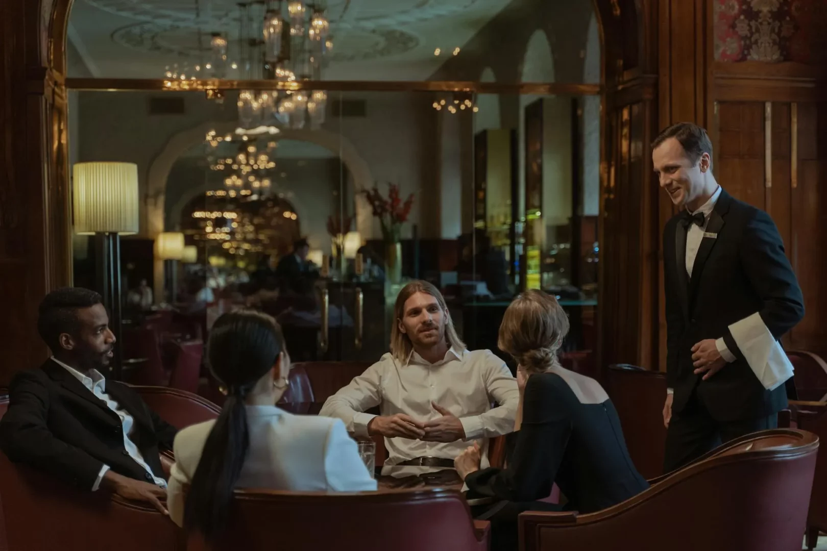 group of male and femal adults eating dinner at vip seating with butler in tuxedo