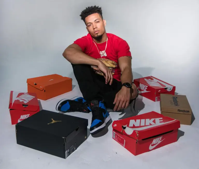 man in red t-shirt sitting next to all his new nike shoe boxes